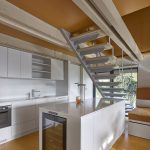 Biela jednoduchá kuchyňa v dome s oranžovým stropom a podlahou