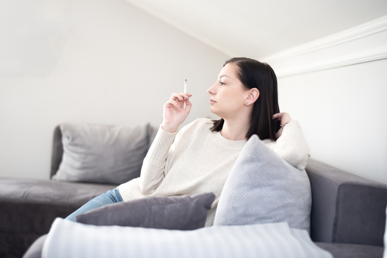 Žena fajčí na gauči v byte