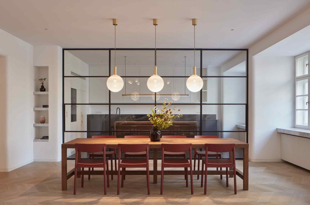 jedáleň s dreveným stolom a presklenou stenou a gulatymi lampami