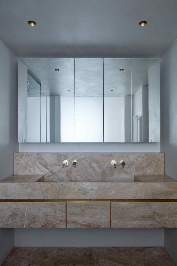 Biela kúpeľňa s mramorovým umývadlom a zrkadlami