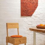 Dizajnová drevená stolička pred bielou tehlovou stenou