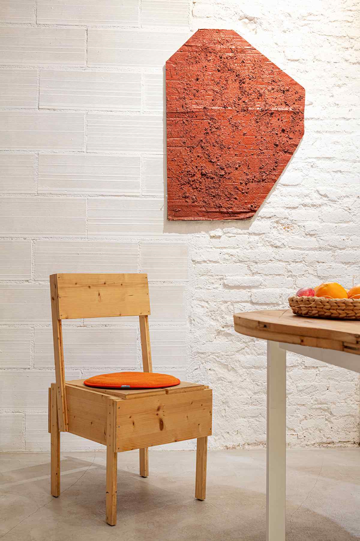 Dizajnová drevená stolička pred bielou tehlovou stenou