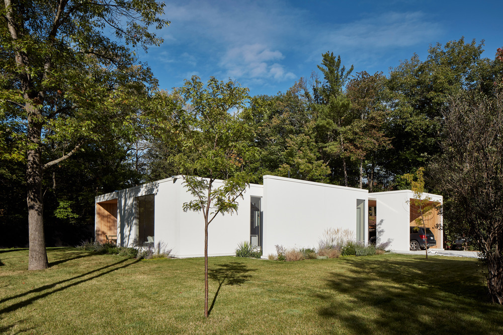 Biely prízemný rodinný dom s veľkými oknami v prírode