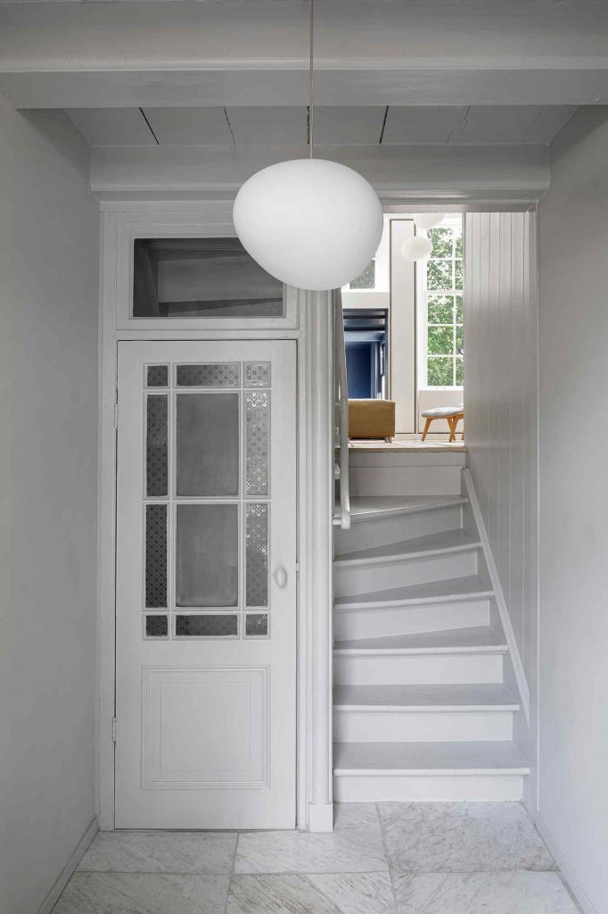 Biela chodba so schodiskom v úzkom holandskom dome