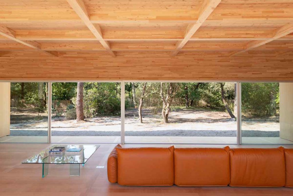 Obývačka s oranžovým gaučom v drevenej vile s presklením