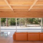 Obývačka s oranžovým gaučom v drevenej vile s presklením