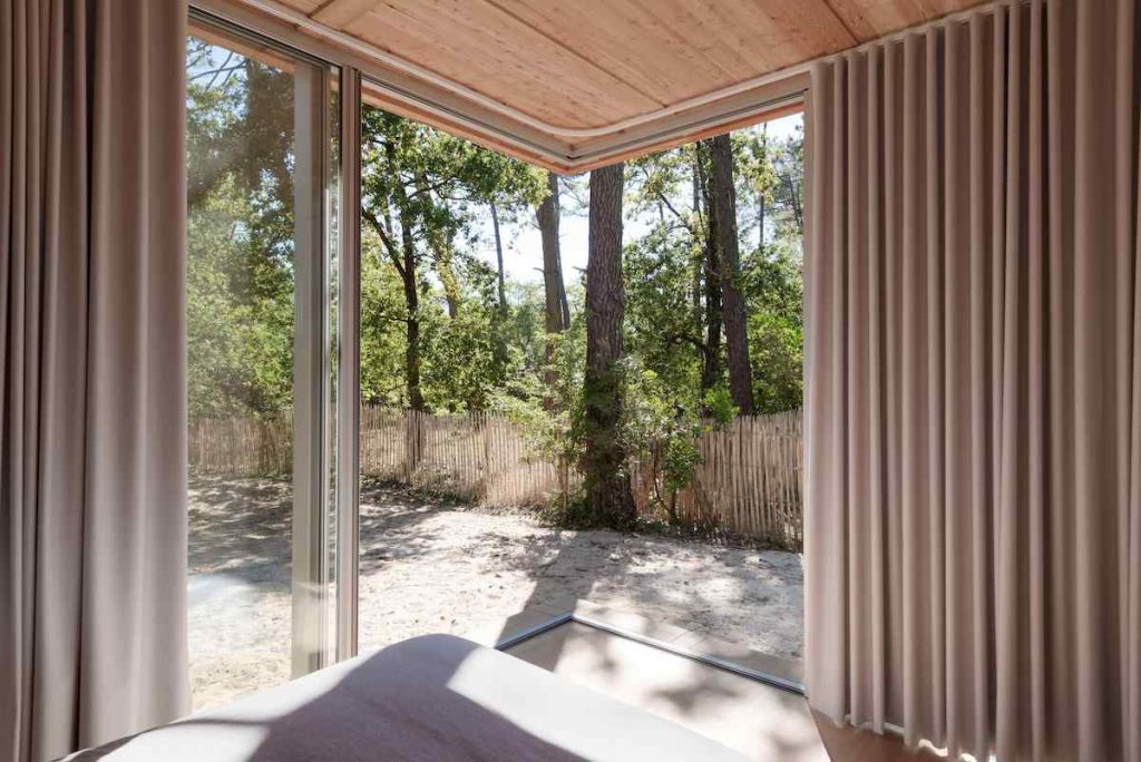 Útulná spálňa v drevenej vile s presklením do záhrady