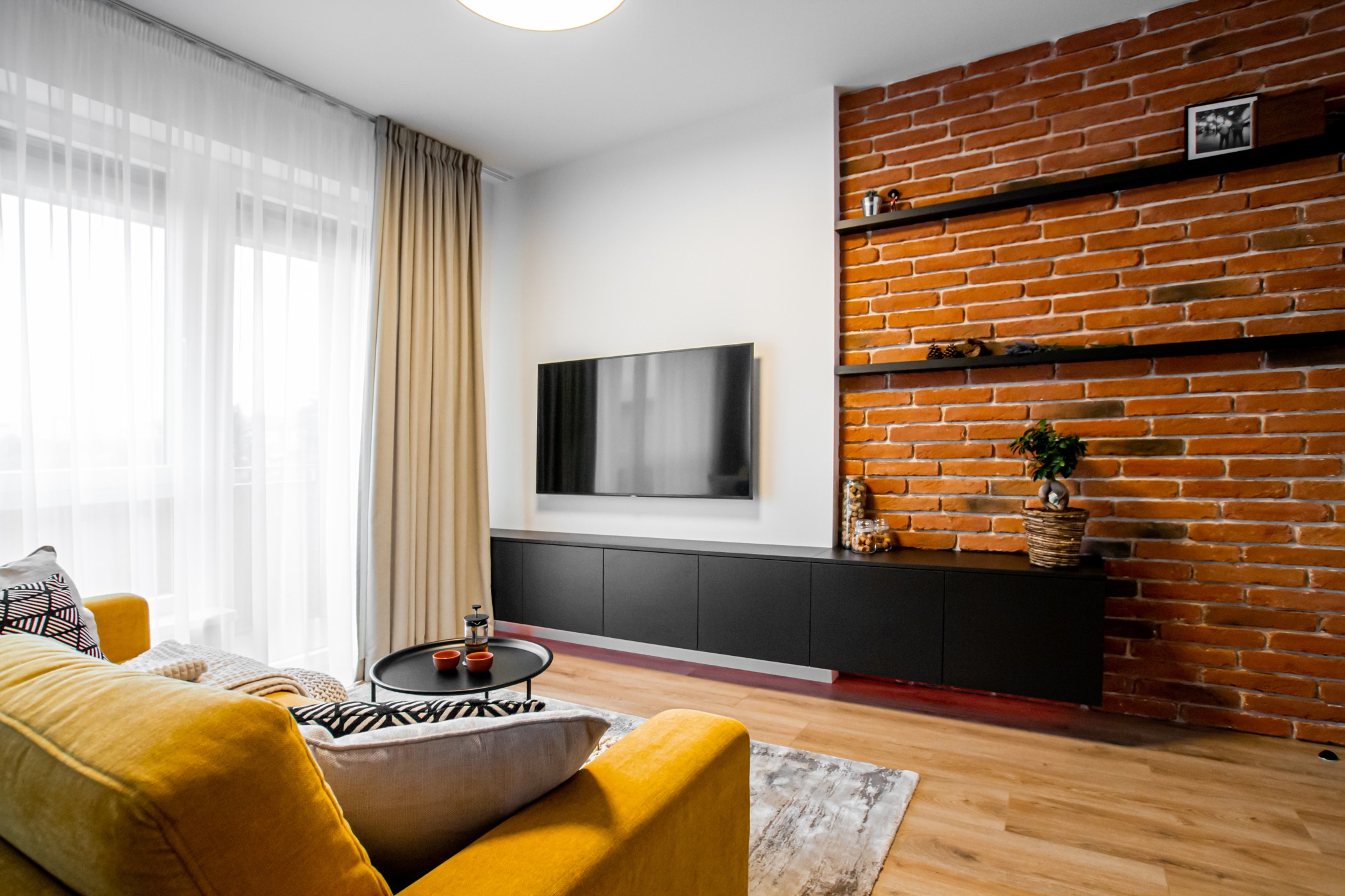 Obývačka so žltým gaučom a tehlovou stenou