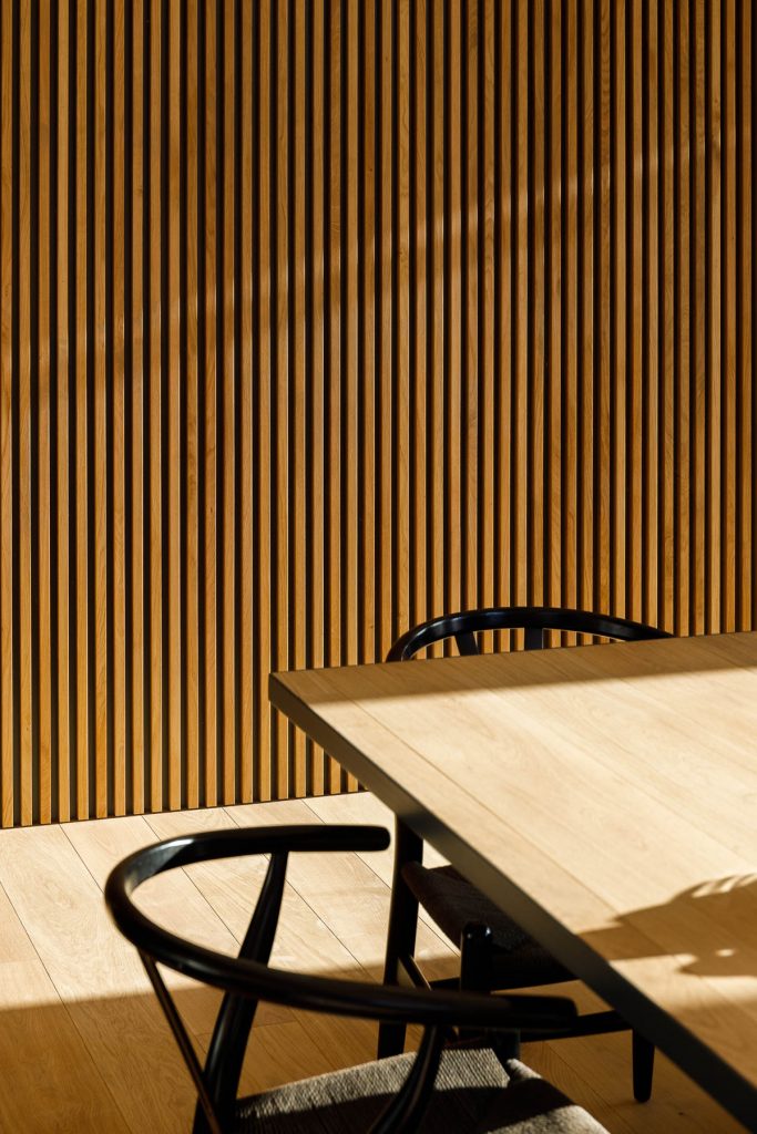 Detail jedálne s lamelami a dizajnovými stoličkami