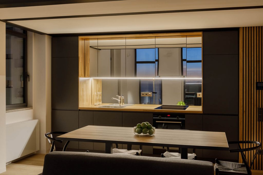Podsvietená moderná hnedá kuchyňaso zrkadlovou zástenou