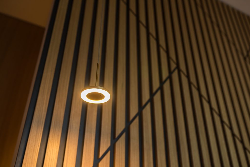 Detail čiernohnedej lamelovej steny so svetlom
