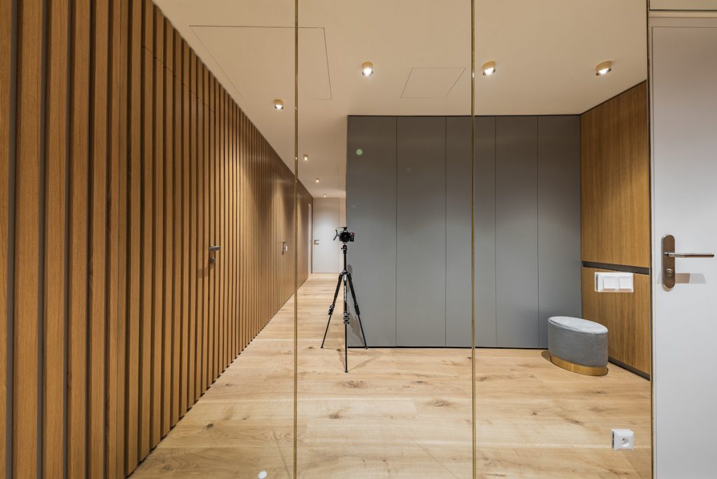 Chodba moderného bytu s lamelovou sivou a zrkadlovou stenou