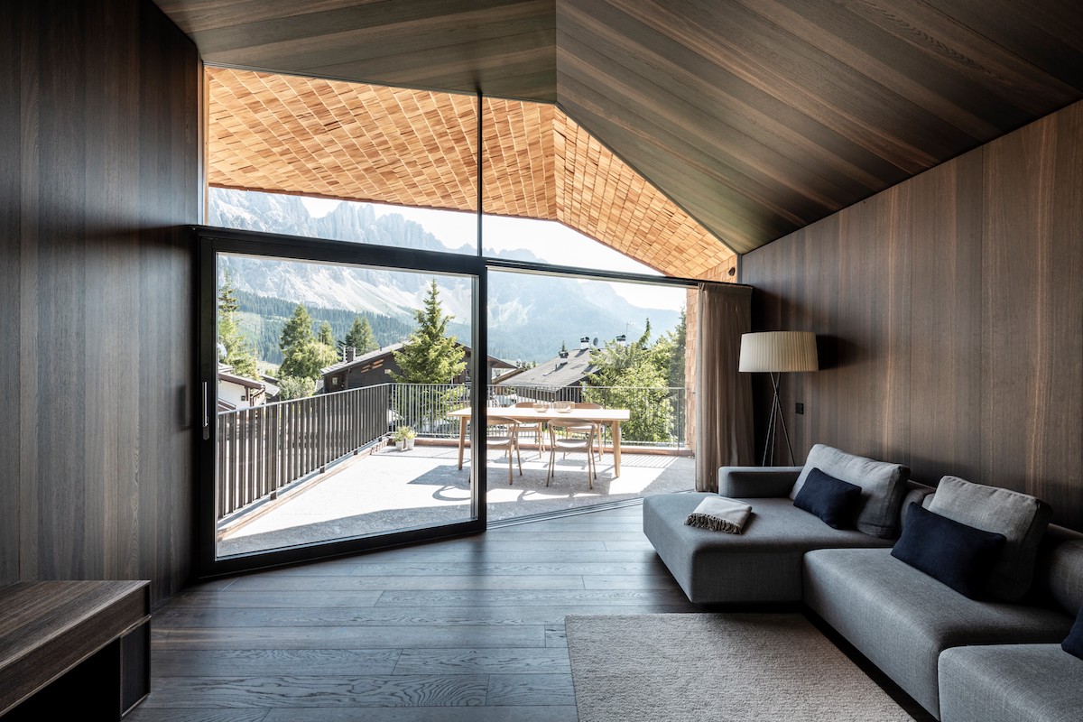 Moderná tmavohnedá obývačka v chate s výhľadom na Alpy