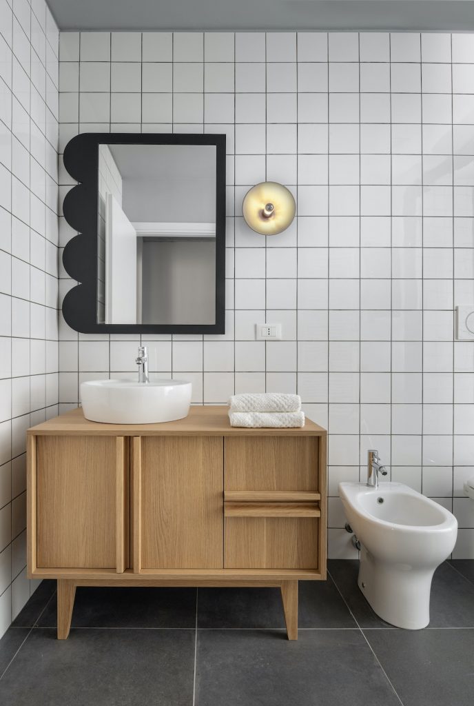 Biela kachličková kúpeľňa s dizajnovým zrkadlom a drevenou skrinkou