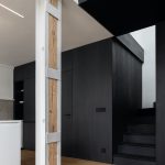 Biela kuchyňa s čiernym boxom a drevenou podlahou