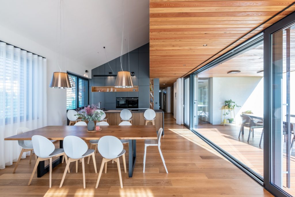 Moderná drevená kuchyňa s jedálňou v dome s veľkou terasou