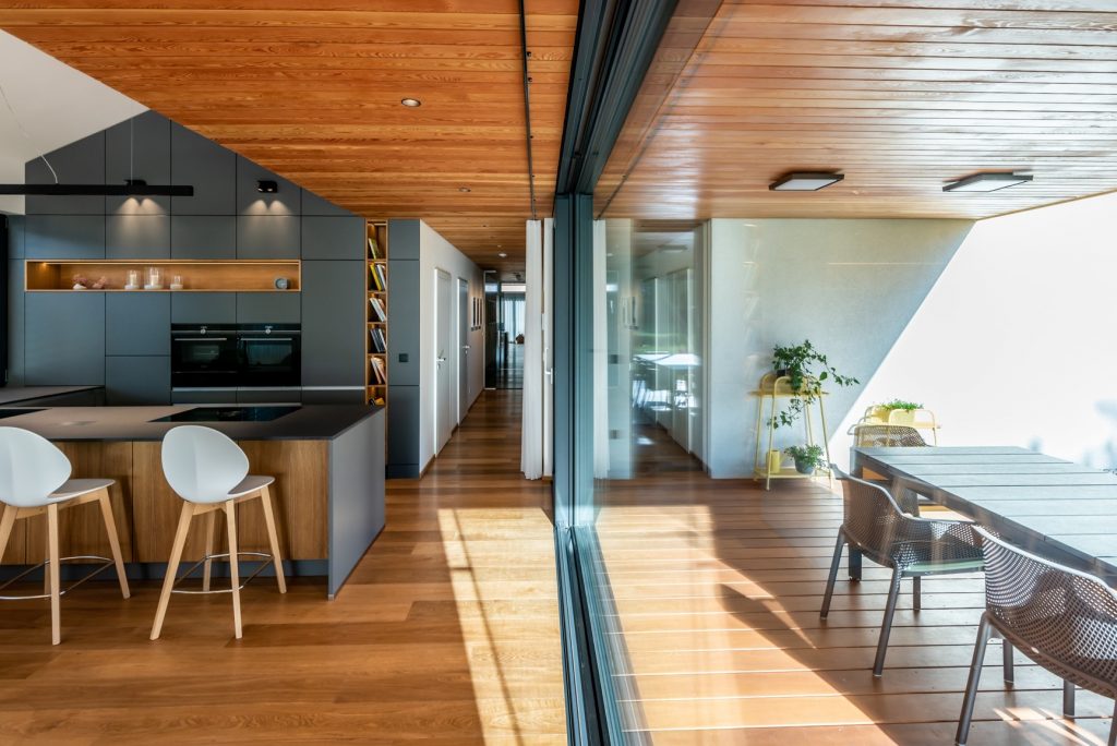 Moderná sivo drevená kuchyňa s jedálňou v dome s terasou