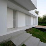 Moderný biely rodinný dom s nepravidelnými oknami v terasovitom pozemku