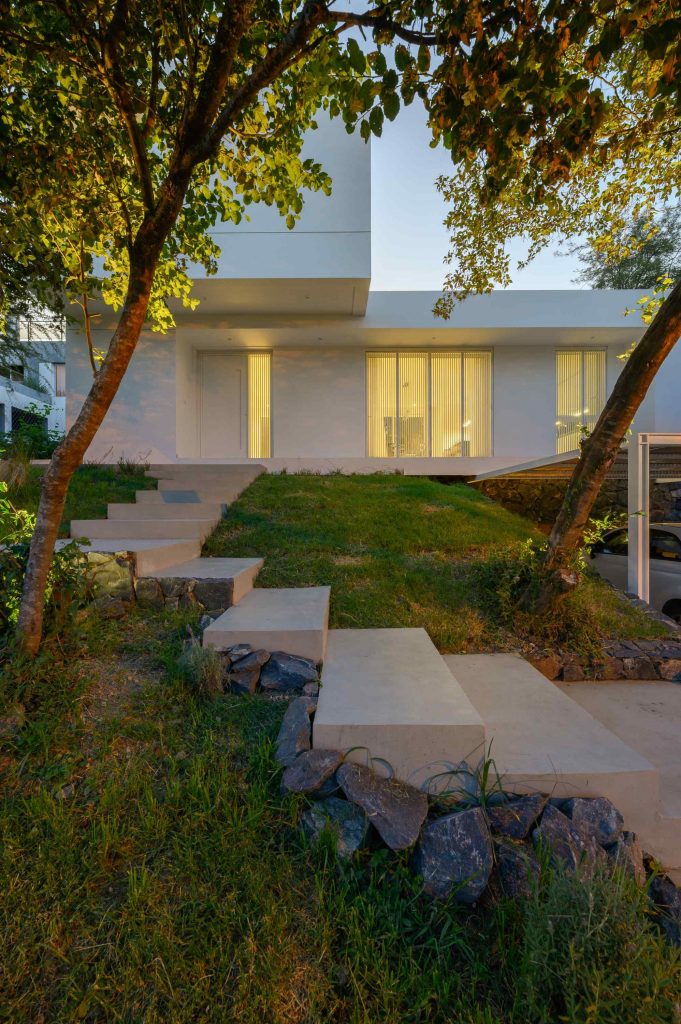 Moderný biely rodinný dom s nepravidelnými oknami v terasovitom pozemku