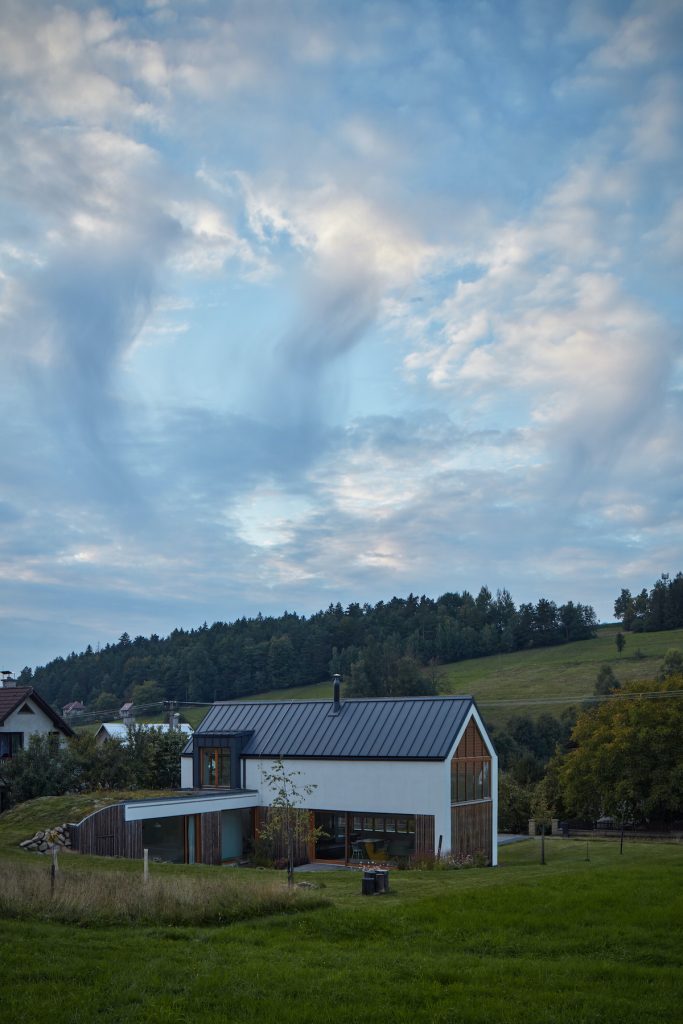 Moderný bielodrevený rodinný dom so šikmou strechou a presklením na lúke