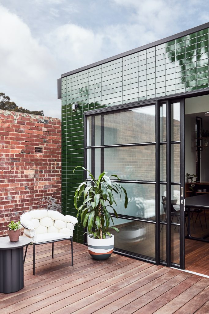 Malý ekologický moderný domček geometrických tvarov so zeleným a hnedým obkladom