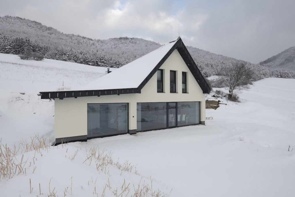 Malý biely dom s presklením pod kopcami Rajeckých hôr