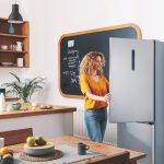 Voľne stojaca chladnička ktorú otvára žena v kuchyni