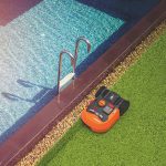Robotická kosačka pri bazéne na trávniku
