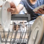 Close-up of a man pulls out clean dishes from the dishwasher.