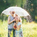 Šťastné deti pod dáždnikom v daždi