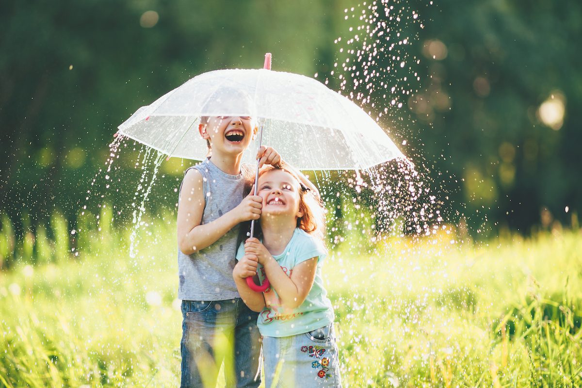 Šťastné deti pod dáždnikom v daždi