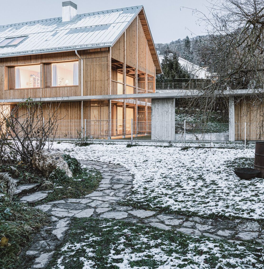 Zastrešeným chodníkom vľavo sa dostanete až k hlavnému vchodu do domu s obdĺžnikovým pôdorysom a sedlovou strechou.