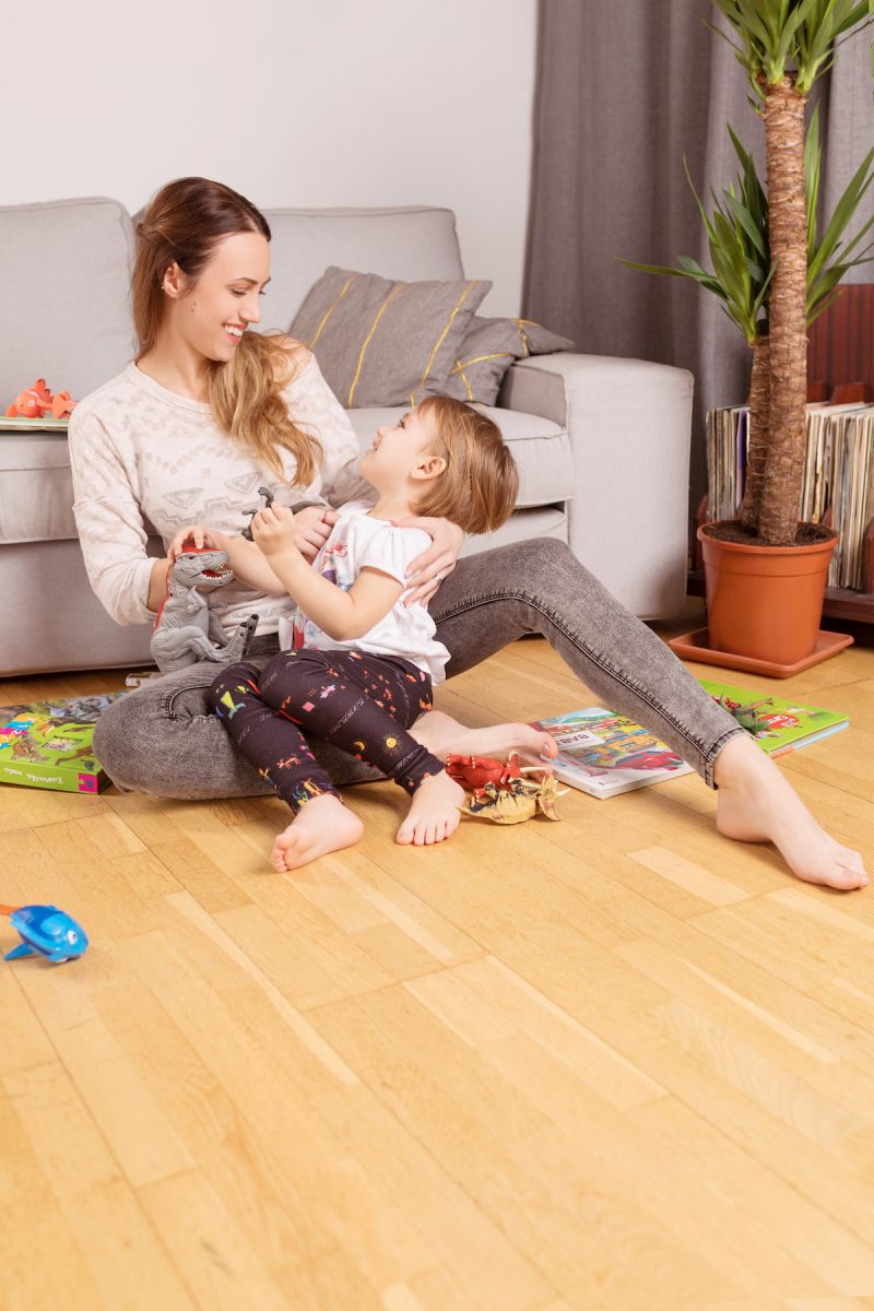 Žena s dieťaťom a hračkami na podlahe v byte