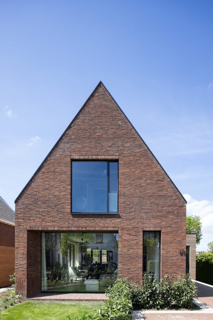 Holandský malý tehlový dvojposchodový dom so šikmou strechou a prístavbou