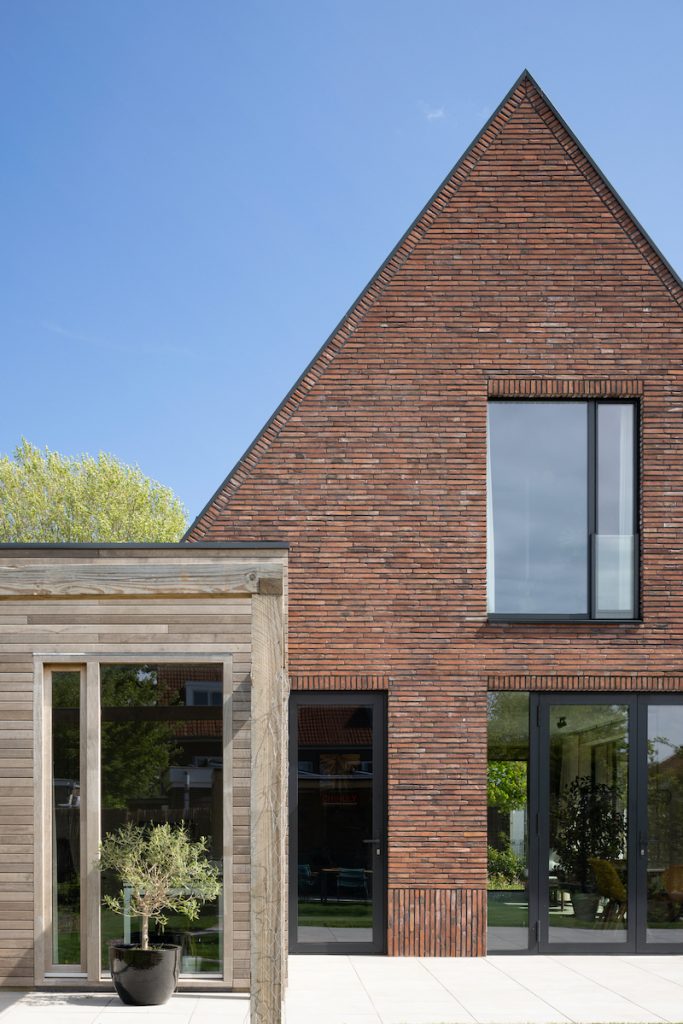 Holandský malý tehlový dvojposchodový dom so šikmou strechou a prístavbou