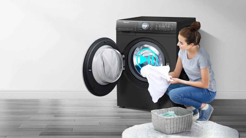 Žena dáva prádlo do otvorenej práčky