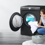 Žena dáva prádlo do otvorenej práčky