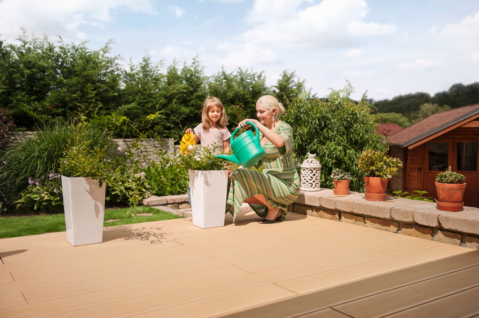 Kompozitná terasa v záhrade a babka s diečatkom polievajúce rastliny