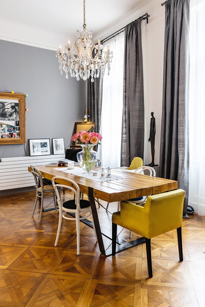 Jedáleň s dreveným stolom na mieru, stoličkami, žltým kreslom a krištáľovým lustrom - Dom hudobníkov v Prahe