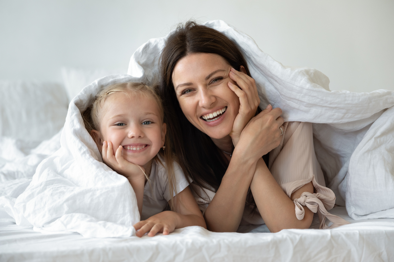 Happy family looking at camera covered with warm white duvet