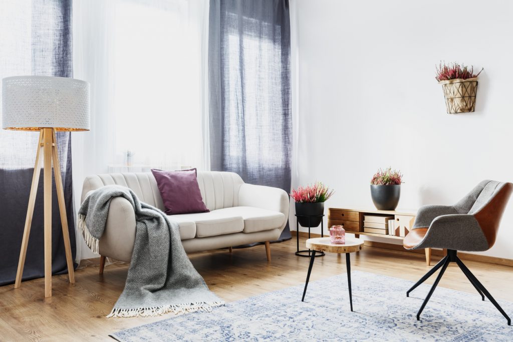 obývačka s dlhým modrým závesom a bledou pohovkou s mgenta vankúšom