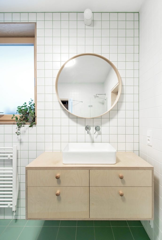 kúpeľňa s bielym obkladom a okrúhlym zrkadlom