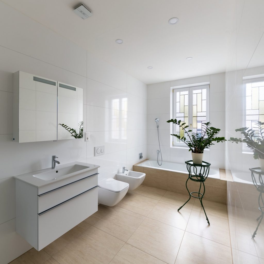biela kúpeľňa s umývadlom, skrinkou a traventínovým béžovým obkladom