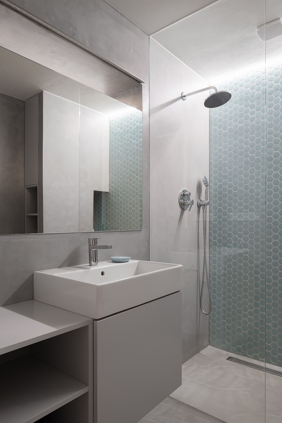 Sivomodrá kúpeľňa s bielym umývadlom a bielym nábytkom, sprchovací kút so sprchou zhora