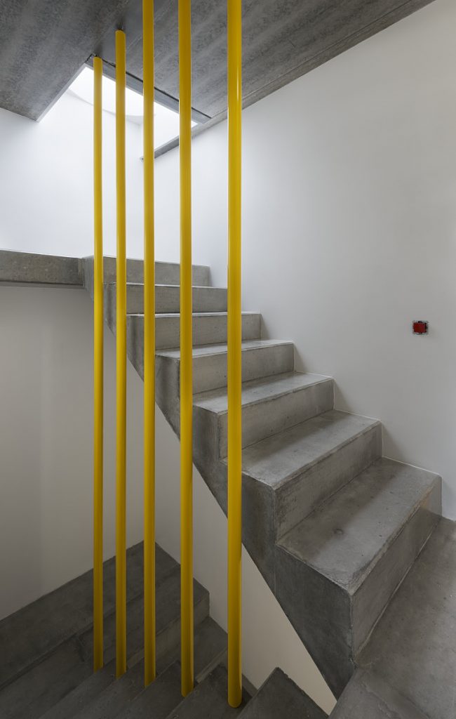 betónové schodisko so žltým zábradlím