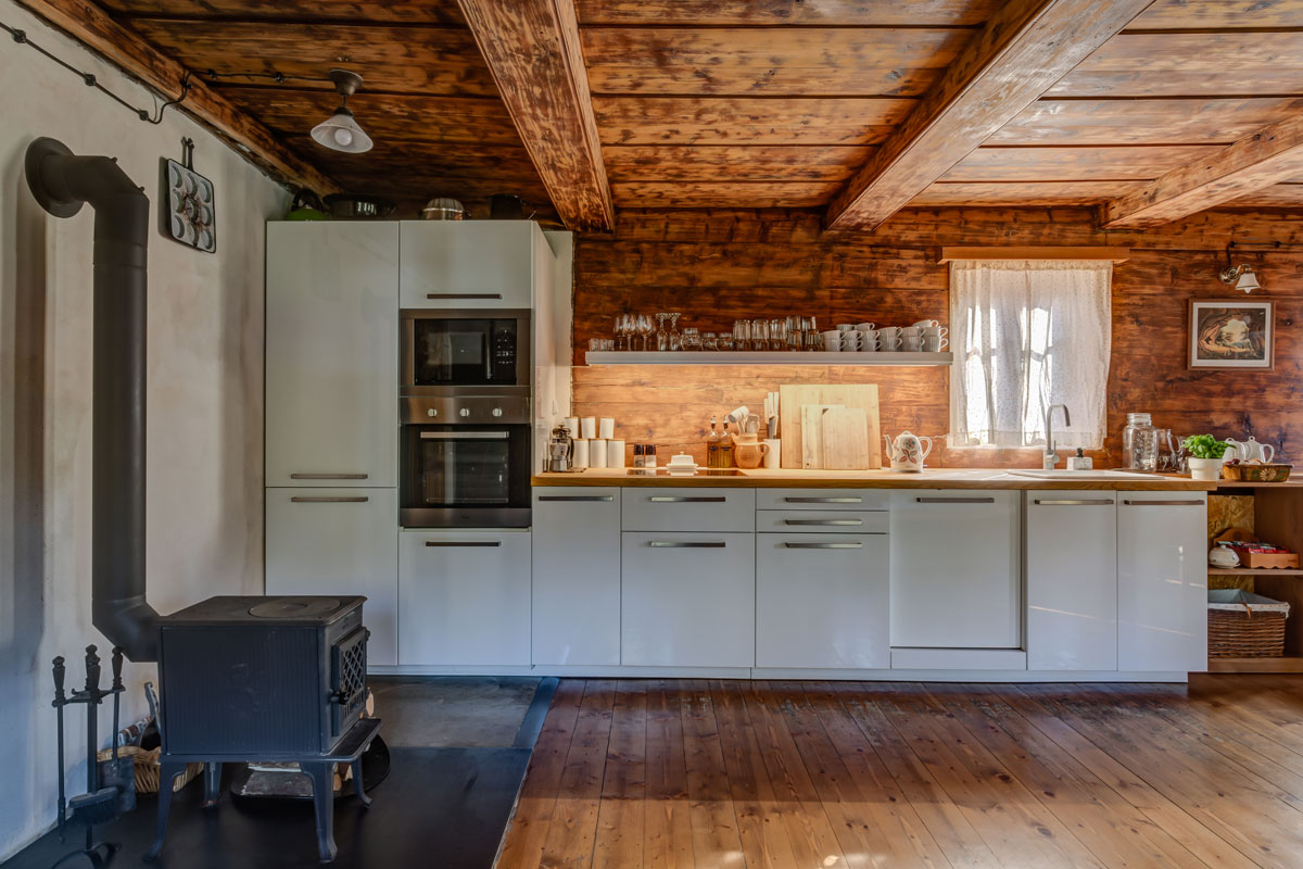 tradičná kuchyňa s trámovým stropom a s modernou bielou kuchynskou linkou