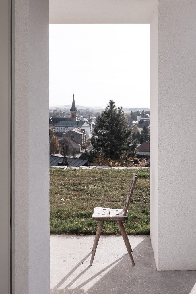 výhľad cez otvorené dvere na krajinu s kostolom, vintage stolička