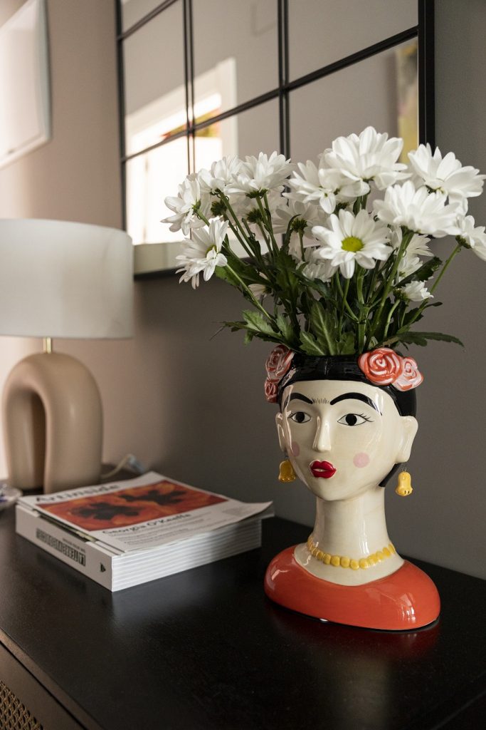 Porcelánová váza v tvare ázijskej ženy s bielymi kvetmi na vintage komode