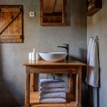 Kúpeľňa s okrúhlym keramickým umývadlom na dradičnom drevenom stolíku v chalupe