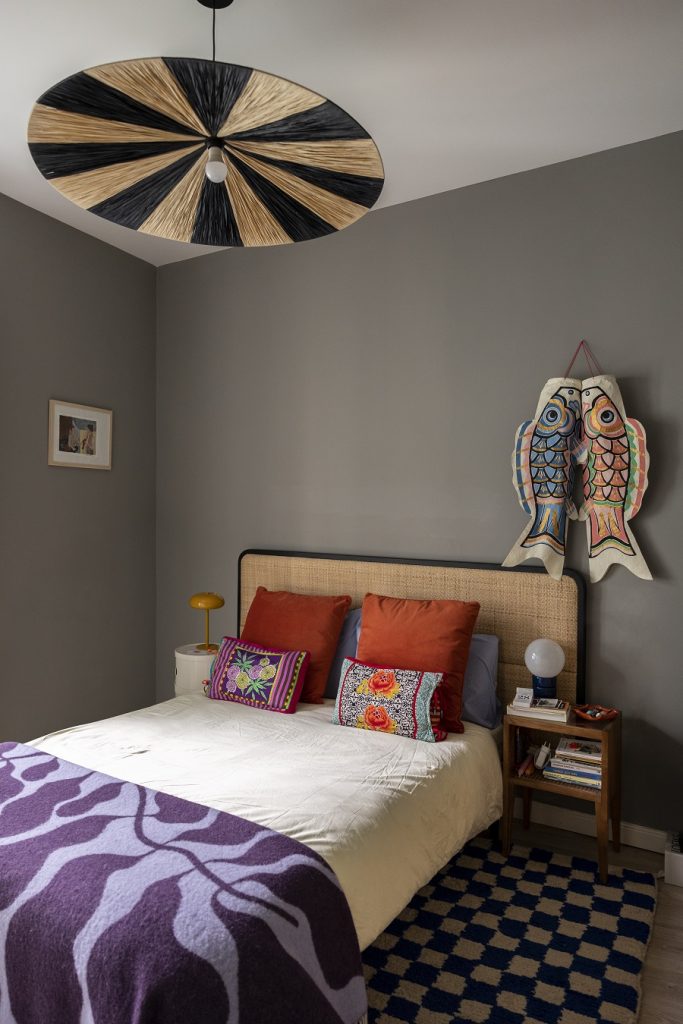 výrazná eklektická spálňa s manželskou posteľou, vzorovanými vankúšmi a orientálnym lustrom